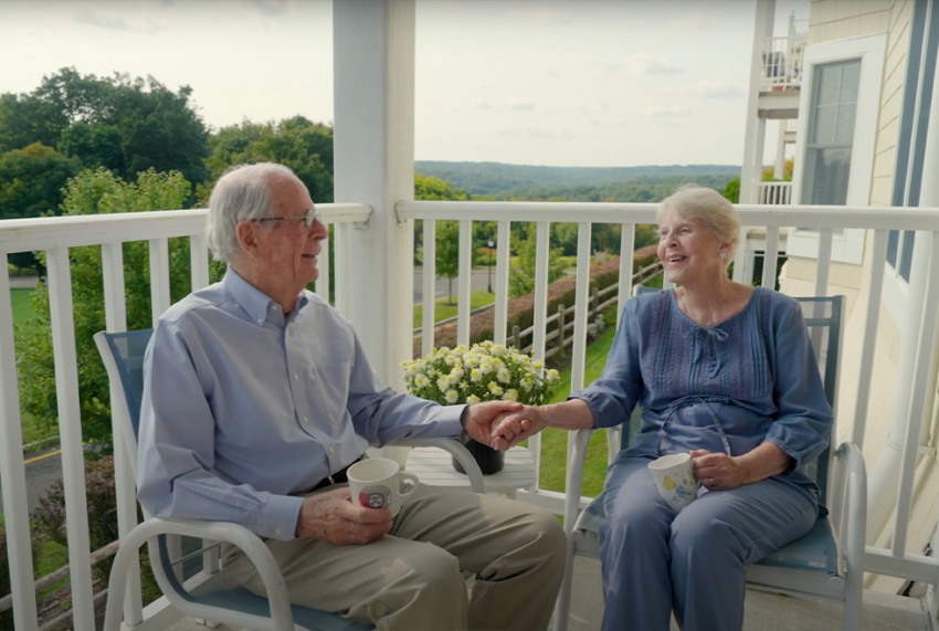 senior couple holding hands on balcony of CCRC